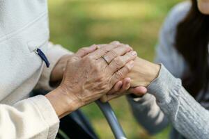 Family relationship Asian senior woman in wheelchair with happy daughter holding caregiver for a hand while spending time together photo