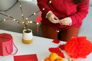 Asian Woman decorated house for Chinese New Year Celebrations. putting traditional pendant to the Chinese Lunar New Year for good luck. Chinese word means blessing photo