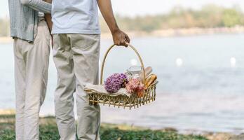 Couple walking in garden with picnic basket. in love couple is enjoying picnic time in park outdoors photo