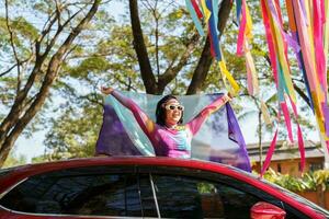 contento asiático mujer apoyo lgbt orgullo desfile en coche. con arco iris de lgbtq o lgbtqia. foto