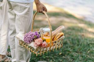 Couple walking in garden with picnic basket. in love couple is enjoying picnic time in park outdoors photo