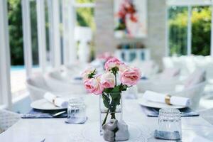 Natural pink roses flower in vase stands on table in a cafe for background photo