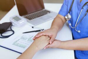 Doctor holding patient's hand, and reassuring woman patient helping hand concept. photo