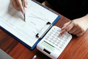 Businessman analyzing investment charts and pressing calculator buttons over documents. Accounting Concept. photo