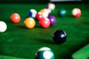 Man's hand and Cue arm playing snooker game or preparing aiming to shoot pool balls on a green billiard table. Colorful snooker balls on green frieze. photo