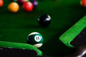 Man's hand and Cue arm playing snooker game or preparing aiming to shoot pool balls on a green billiard table. Colorful snooker balls on green frieze. photo