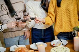 Cheerful friends enjoying home Birthday holiday party. Asian Friends cheering drinking red wine celebrating Christmas or New Year party photo