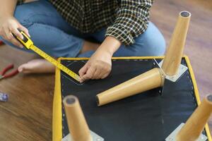 Asian Woman self repairs furniture renovation using equipment to diy repairing furniture sitting on the floor at home photo