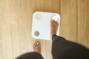perder peso. grasa dieta y escala pies en pie en electrónico escamas para peso control. medición instrumento en kilogramo para dieta. foto