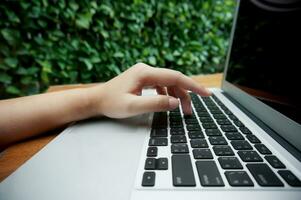 Working by using a laptop computer on wooden table. Hands typing on a keyboard. photo