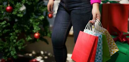 contento asiático niña sostener compras pantalones Navidad presente. alegre mujer con Navidad nuevo año invierno rebaja foto