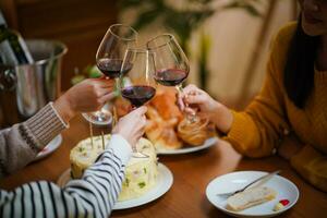 Cheerful friends enjoying home Birthday holiday party. Asian Friends cheering drinking red wine celebrating Christmas or New Year party photo