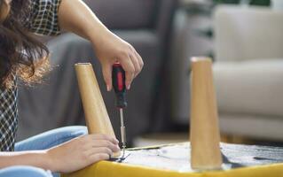 Asian Woman self repairs furniture renovation using equipment to diy repairing furniture sitting on the floor at home photo