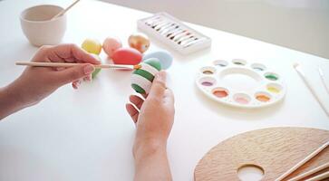 Woman painting Easter eggs at home. family preparing for Easter. Hands of a girl with a easter egg photo