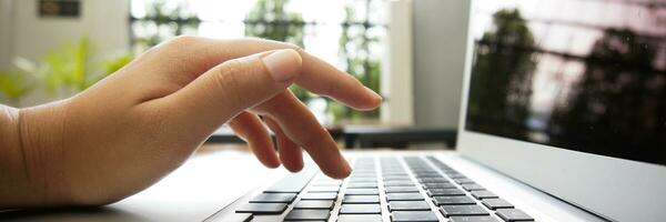 Working by using a laptop computer on wooden table. Hands typing on a keyboard. photo