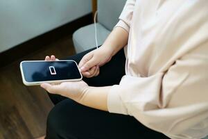 Woman hands Charging mobile phone battery with low battery. plugging a charger in a smart phone  with energy bank powerbank power charger Modern lifestyle energy technology concept photo