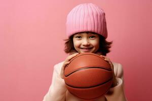 Girl holding basketball ball on pink background photo