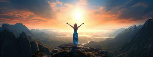 Woman standing on top of the mountain with arms outstretched against the mountain scenery photo