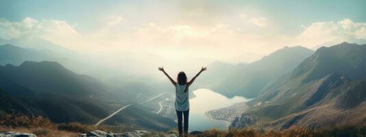 Woman standing on top of the mountain with arms outstretched against the mountain scenery photo