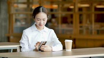 Cheerful smiling Asian woman looking at tablet typed documents in store front video