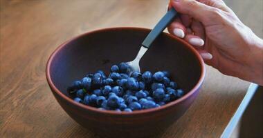 Galubika. A girl with beautiful nails eats blueberry from a clay plate. video