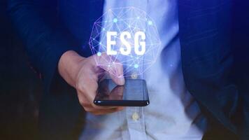 ESG icon concept use a smartphone to analyze ESG for environmental, social and governance in sustainable and ethical business on the Network connection, businessman pressing button on screen. photo