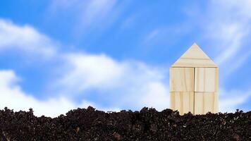 Closed up tiny toy wooden house model on ground with blue sky background, concept of growth, real estate, investments for the purchase of real estate. Home concept. photo