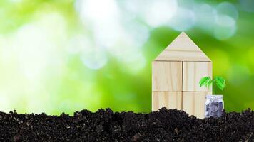 Finance, Model wooden house and coins money in glass bottle with Tree growing on sunlight bokeh green nature background, Saving money, Business investment and loan for real estate buy house concept. photo