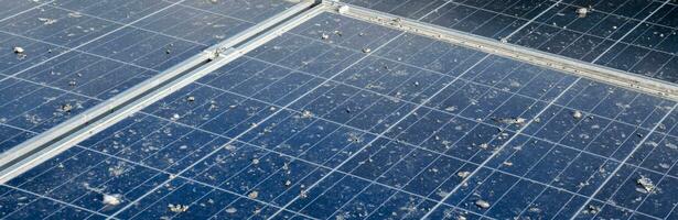 Upper surface of solar rooftop which has been used for a long time is stained with dust, bird droppings, dirt, smog and rainwater stains, concept for cleaning, washing and maintainance, cropped shot. photo