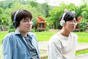 joven asiático adulto Pareja vistiendo auriculares, sesión, escuchando a música y gasto gratis hora juntos en frente de su casa, bueno relación y mejor amigos concepto. foto