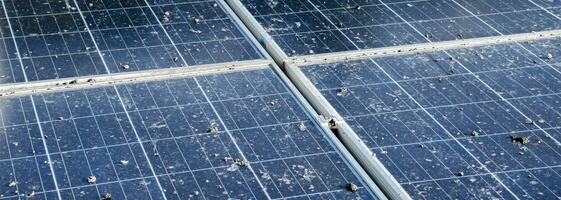 Upper surface of solar rooftop which has been used for a long time is stained with dust, bird droppings, dirt, smog and rainwater stains, concept for cleaning, washing and maintainance, cropped shot. photo