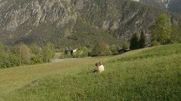 ein Mädchen und ein Junge halten ein Haus ausgeschnitten Sitzung im das Gras auf ein Hügel video