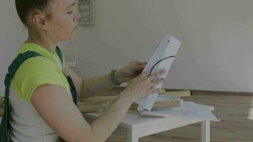 une femme dans salopette est travail sur une pièce de papier carton video