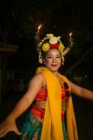 a traditional Javanese dancer dances with colorful flowers on her fist while on stage photo