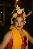 a traditional Javanese dancer dances with colorful flowers on her fist while on stage photo