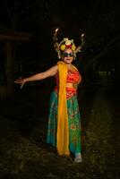 a traditional Javanese dancer stands and dances with a flexible body while wearing sunglasses photo