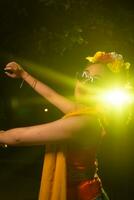 a beautiful Sundanese dancer poses and dances in a glamorous dress and scarf in front of the stage light photo
