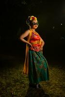 a traditional Javanese dancer stands and dances with a flexible body while wearing sunglasses photo