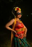 a traditional Javanese dancer stands and dances with a flexible body while wearing sunglasses photo