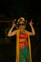 portrait of a traditional Javanese dancer dancing with very beautiful hand movements while wearing sunglasses photo