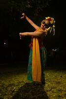 a traditional Indonesian dancer dancing with the body twisting on stage photo