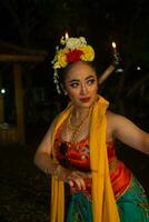 portrait of a traditional Sundanese dancer dancing with an orange scarf hanging down her body photo