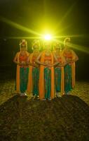 a group of Indonesian traditional dancers dance with their friends in front of the stage lights photo