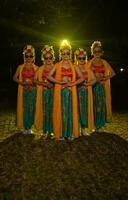 un grupo de indonesio tradicional bailarines danza con su amigos en frente de el etapa luces foto