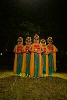 un grupo de tradicional javanés bailarines en pie en disfraces y naranja chales y Gafas de sol en su ojos foto