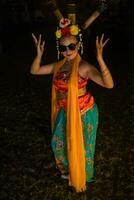 un indonesio tradicional bailarín bailes en Gafas de sol y un naranja disfraz con un hermosa chal foto