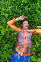 an Indonesian woman is lying on a green tea garden while on vacation photo