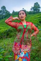 an Asian woman in a red dress is standing in front of a tea garden photo