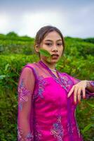 an Asian woman in a pink dress is standing in front of a tea garden photo