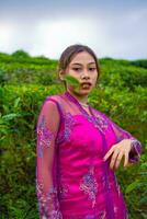 an Asian woman in a pink dress is standing in front of a tea garden photo